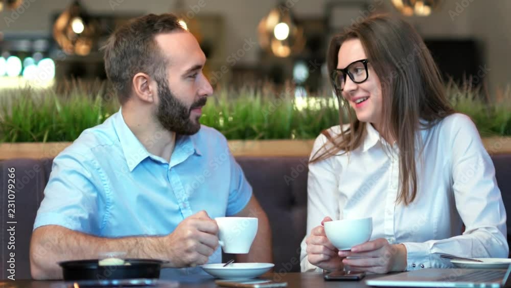 Business partners man and woman smiling and having fun enjoying informal meeting in cafe Business partners man and woman smiling and having fun enjoying informal meeting in cafe