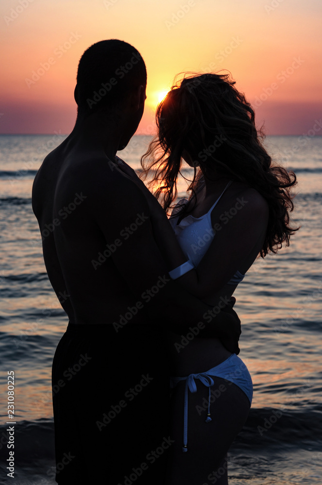 Silhouette Of Couple Embracing On A Beach At Sunset