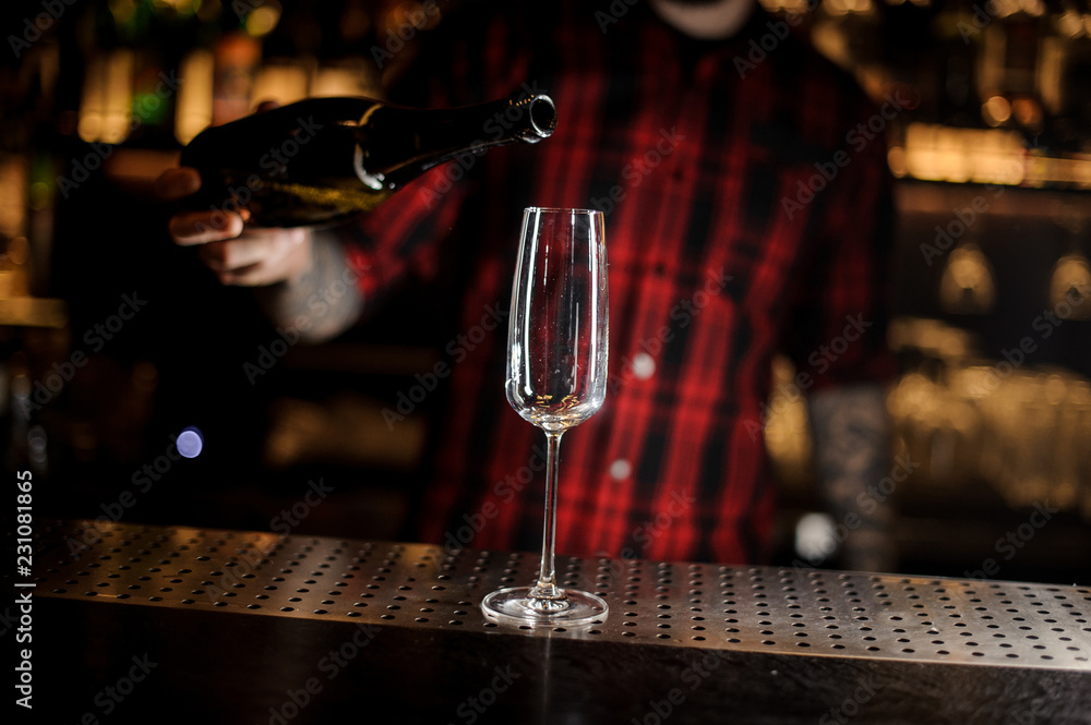Bartender pourring a champagne from a bottle to a glass