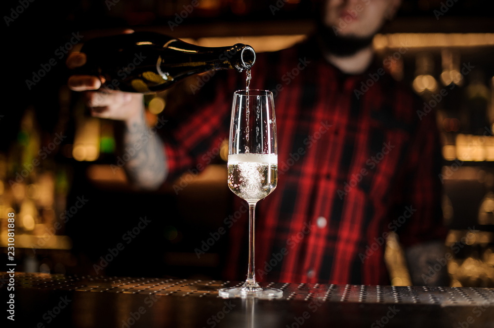 Bartender pourring a delicious champagne from a bottle to a glass Bartender pourring a delicious champagne from a bottle to a glass