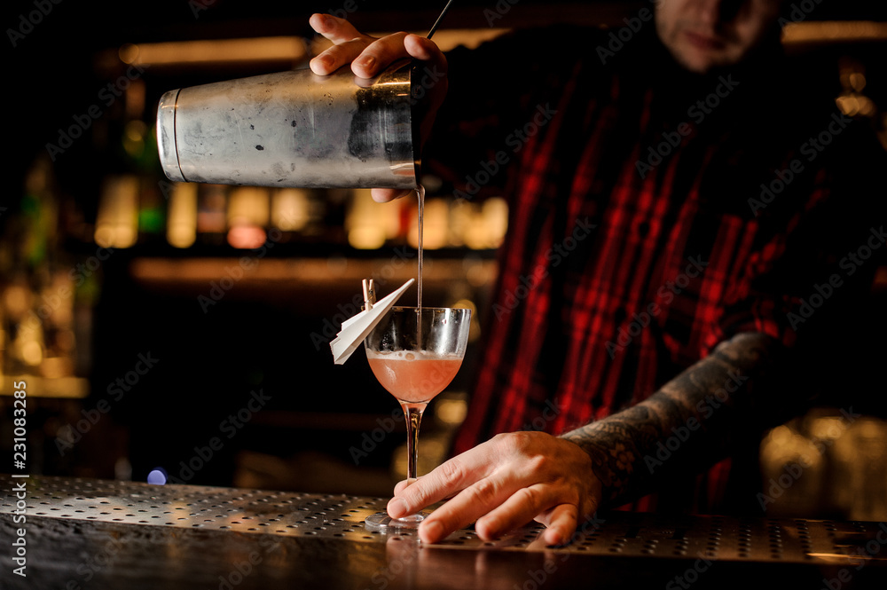 Bartender pouring Paper Plane cocktail into a decorated glass
