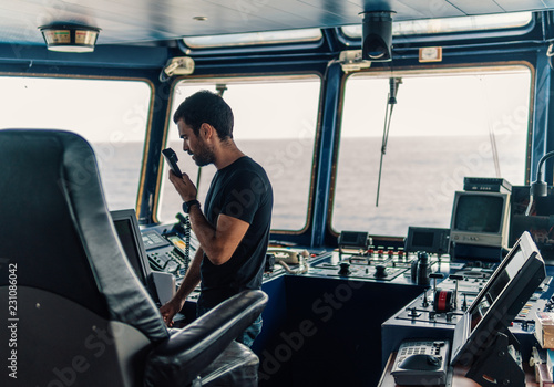 Marine navigational officer is reporting by VHF radio during navigation watch. Bridge GMDSS watch photo