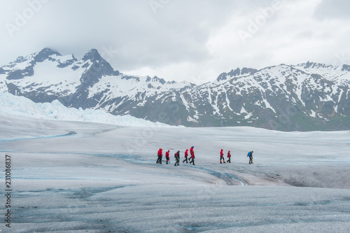 Foto Hikers in colorful coats walking on a glacier surrounded by mountains