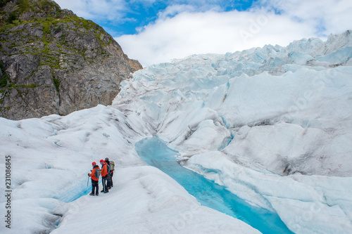 Hikers standing near colorful blue meltwater on a glacier in Alaska