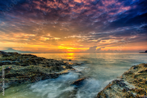 A long exposure picture Beautiful Scenery cloudy Sunset With Stone and wave As Foreground