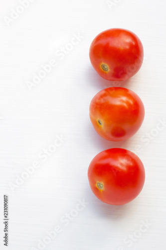 Tomatoes on white wooden background.