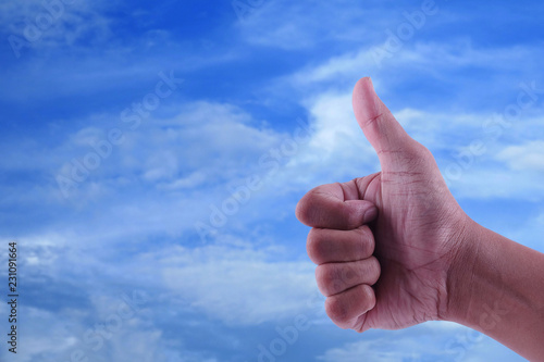 Male hand showing thumb up sign on a blue sky background