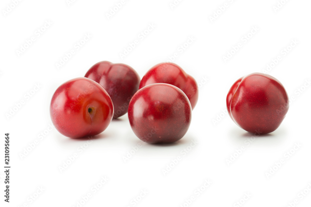 Very ripe fresh harvested plums, isolated on white. Five shiny red plums on white surface. Very ripe fresh harvested plums, isolated on white. Five shiny red plums on white surface.