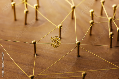 Linking entities. Dispute or conflict, or Bottleneck between two entities. Network, networking, social media, internet communication abstract. Web of gold wires on rustic wood. photo
