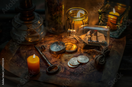 Old coins  key  burning candles and compass on vintage map