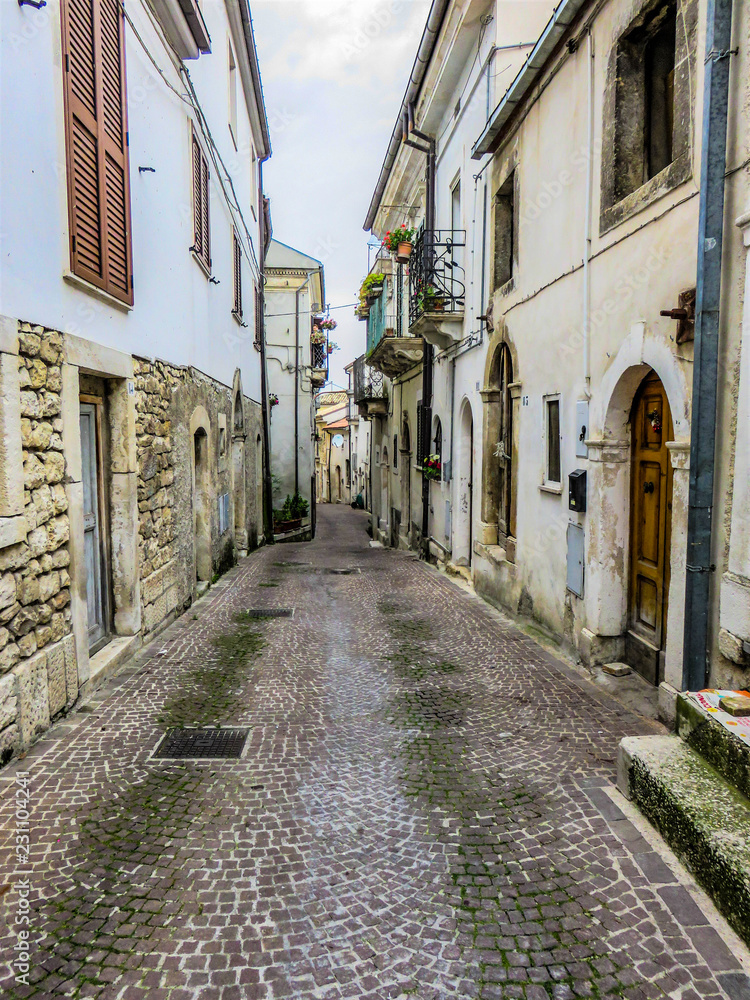 A narrow Italian, cobblestone street with old houses on each side.
