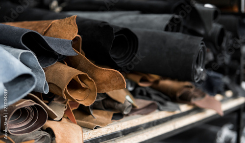 Different pieces of leather in a rolls. The pieces of the colored leathers. Rolls of natural brown and black and other leather. Raw materials for manufacture of bags, shoes, clothing and accessories. photo