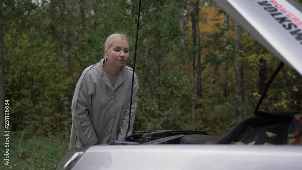 The woman is waiting for help after her car broke down on the road. The woman is waiting for help after her car broke down on the road.