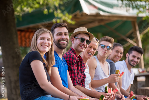 friends enjoying watermelon while sitting on the wooden bridge