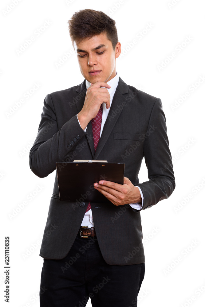 Young handsome businessman reading on clipboard while thinking Young handsome businessman reading on clipboard while thinking