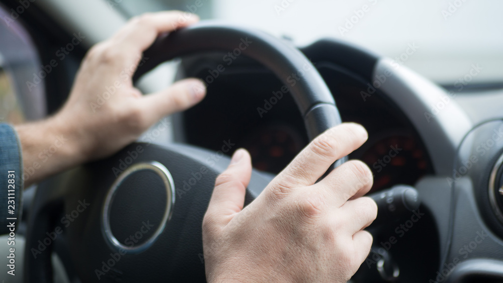 Male hands on steering wheel inside car, selected focus Male hands on steering wheel inside car, selected focus
