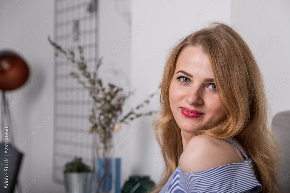 Portrait of a nice blonde girl in blue dress in the room