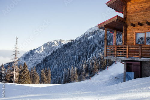 Winter vacation holiday alpine wooden house skiing relax leisure resort in the mountains covered with snow and blue sky.Dramatic cottage scene in Austrian Alps snowy panoramic landscape on a sunny day photo