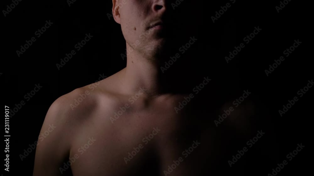 Naked upper body of a man. A man posing in the Studio in the dark. Naked upper body of a man. A man posing in the Studio in the dark.