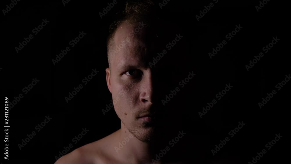 Angry man in the dark. Only half of the face is highlighted. Angry man in the dark. Only half of the face is highlighted.