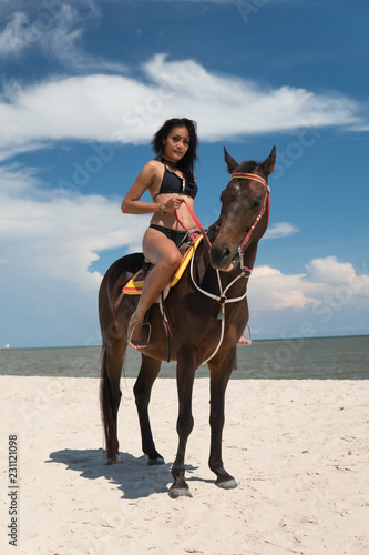 Sexy girl riding horse at beach. Fair tan skin and smooth.