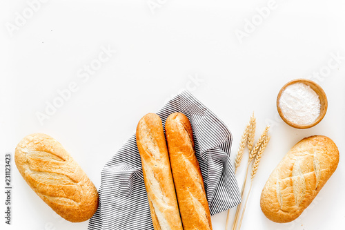 White bread. Fresh rustic homemade bread and loaf on tablecloth decorated with ears and flour on white background top view copy space