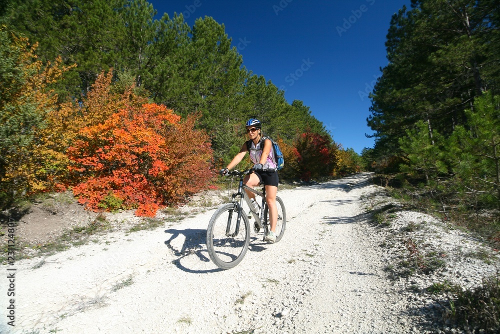 A young woman riding a bike in the autumn forest.