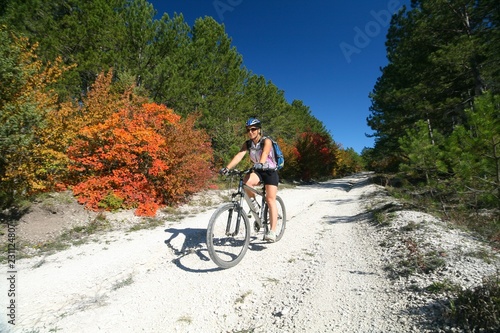 A young woman riding a bike in the autumn forest.