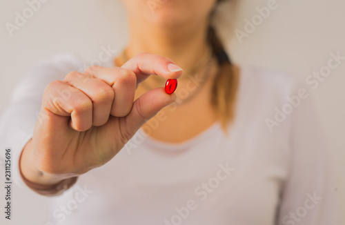 Woman holding big single red pill.