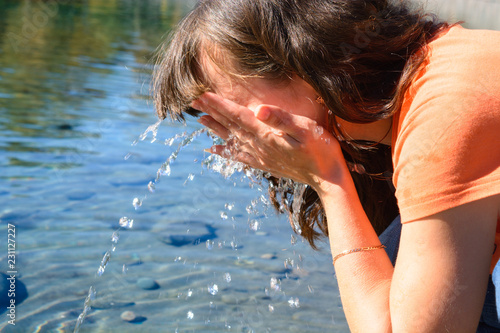 Traveler pulled a handful of clean water from a pond to wash his face photo