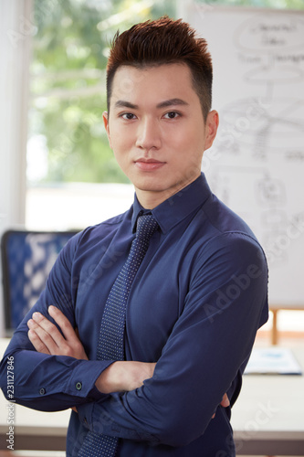 Portrait of handsome businessman in blue shirt standing with arms crossed with confident face