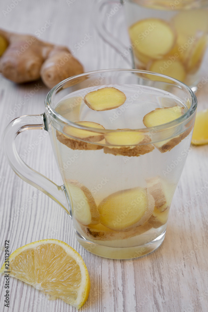 Cup of homemade ginger tea with lemon on white wooden table, side view. Closeup. Cup of homemade ginger tea with lemon on white wooden table, side view. Closeup.