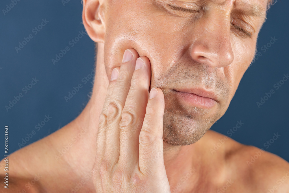 Sad depressed man in pain holding his cheek. Portrait of a man on blue background. emotion facial expression. feelings and people reaction. Toothache Sad depressed man in pain holding his cheek. Portrait of a man on blue background. emotion facial expression. feelings and people reaction. Toothache