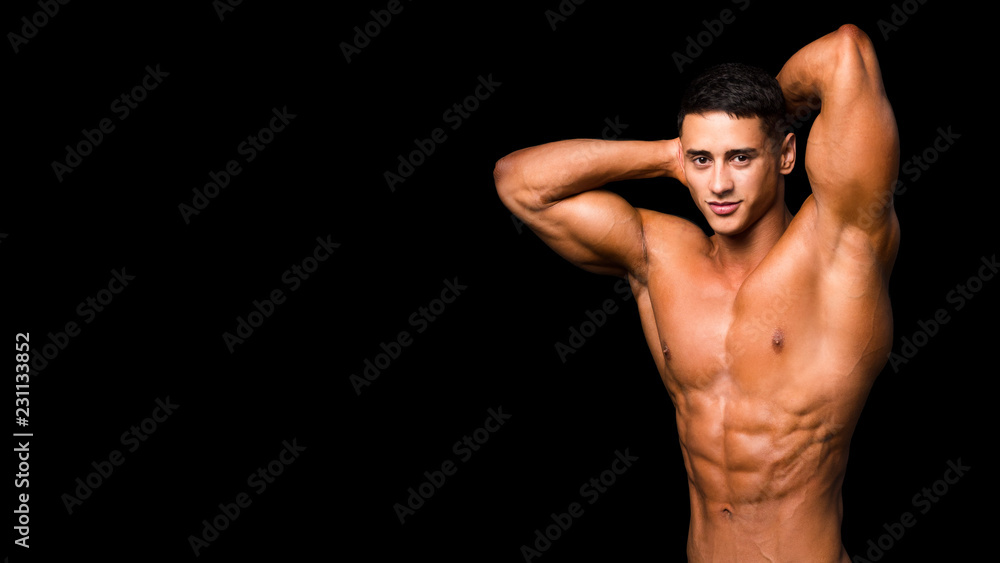 Young handsome sportsman bodybuilder weightlifter with an ideal body, after coaching poses in front of the camera, abdominal muscles, biceps triceps.