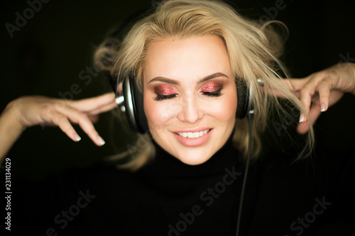 Beautiful girl listening to music against dark background