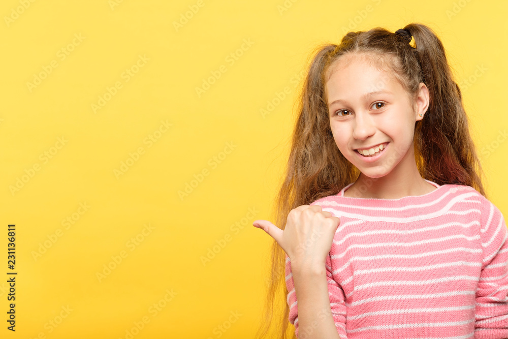 look left. smiling girl pointing her index finger to a virtual object or text. empty space for advertisement.
