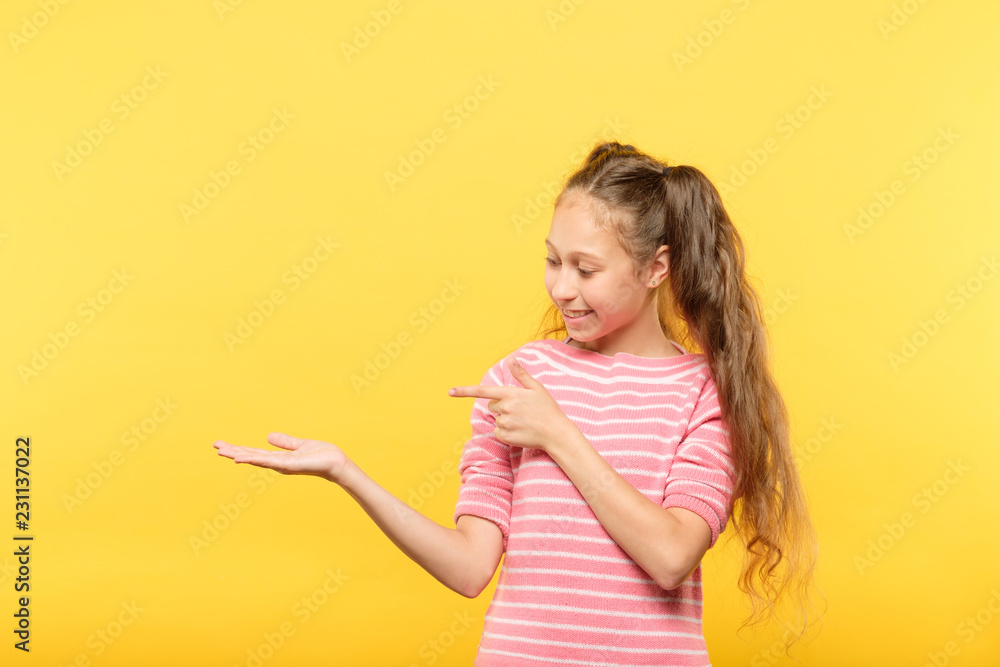 smiling cute girl looking at virtual object in hands and pointing to it. empty space for advertisement or product placement. smiling cute girl looking at virtual object in hands and pointing to it. empty space for advertisement or product placement.