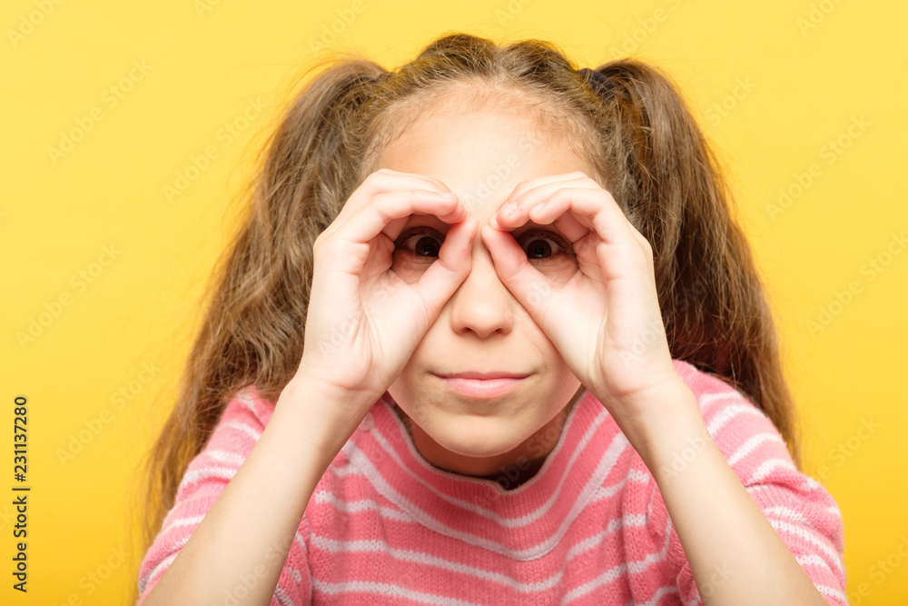 girl pretending to look through binoculars made of hands. search concept. girl pretending to look through binoculars made of hands. search concept.