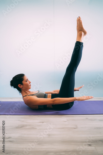 Картината върху платно Young sporty attractive woman practicing yoga, pilates, doing Staff exercise at yoga studio, side view