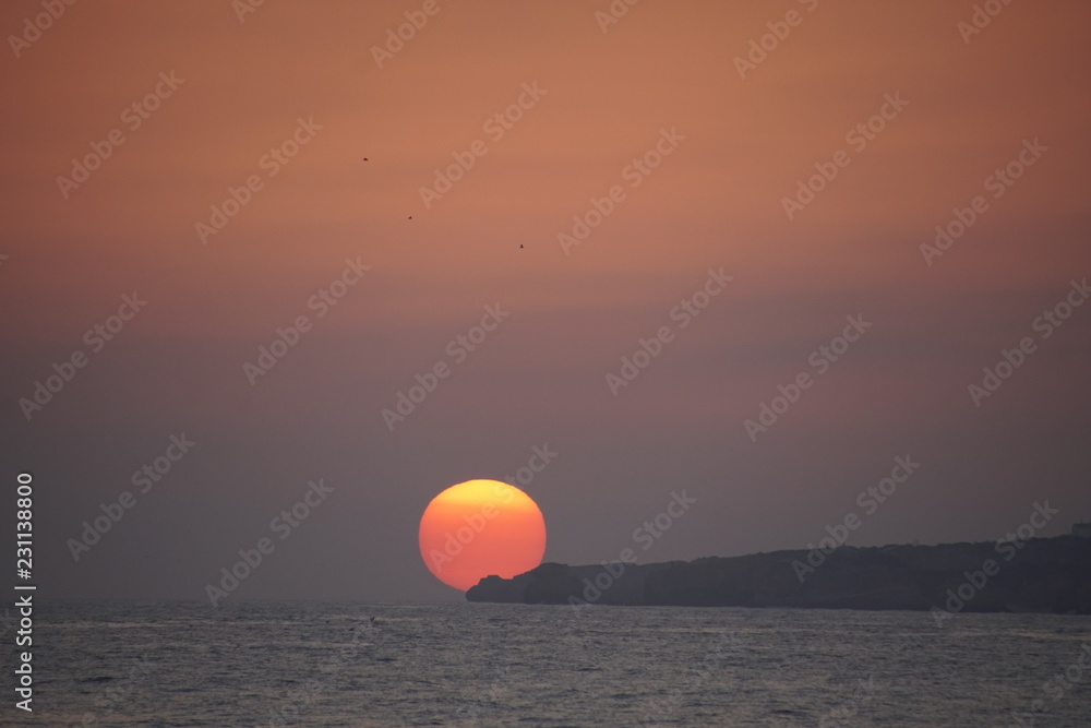 Ocean in the evening. Sunset over the waves. Clouds and bright colors of the evening sky. Orange red azure Ocean in the evening. Sunset over the waves. Clouds and bright colors of the evening sky. Orange red azure