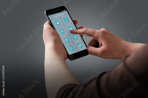 Wallpaper Mural Closeup of woman's hands with black smartphone and Smart home application icons interface design. House automation concept. Torontodigital.ca