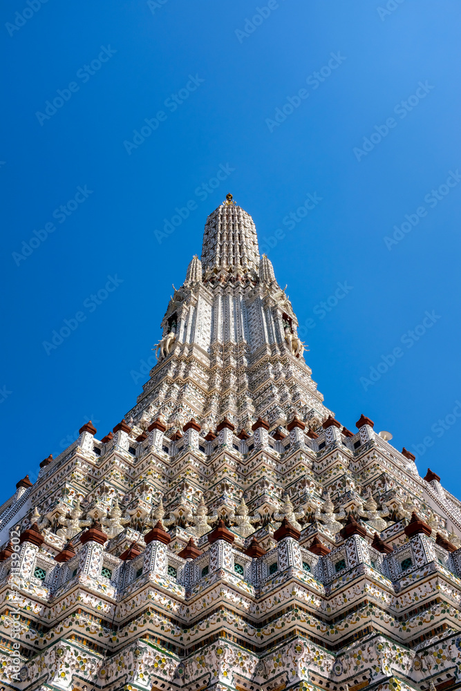 White stupa pagoda in temple of dawn or Wat Arun in Thailand under bright blue sky