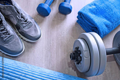 Fototapeta Naklejka Na Ścianę i Meble -  Sneakers, two blue dumbbells, a towel and a workout mat. Sport fitness items on light grey wooden background with empty text space. Active lifestyle, weight loss, body care concept. Top view.