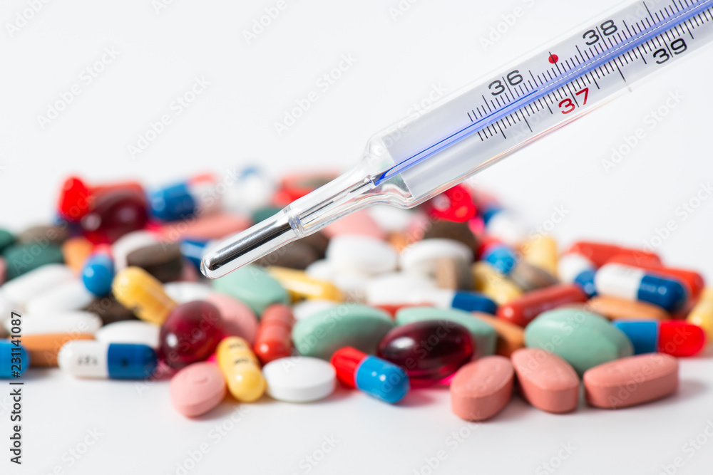 Fever thermometer with small medications on a white background Fever thermometer with small medications on a white background