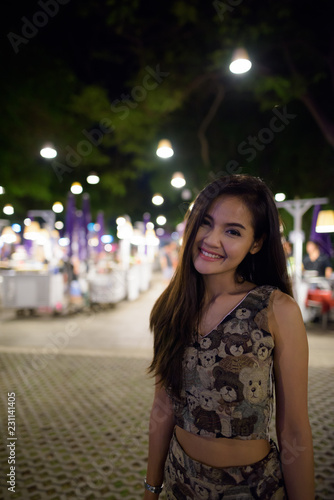 Young happy beautiful Asian woman smiling against scenic view of