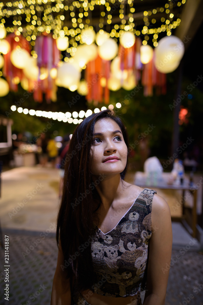 Fototapeta premium Young beautiful Asian woman thinking against scenic view of ligh