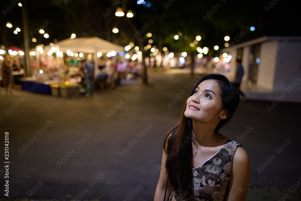 Young happy beautiful Asian woman smiling and thinking against t