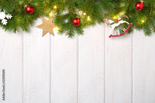 Christmas frame greeting card. Brushing a branch of a Christmas tree on a white background with red balls and figurines of shiny stars, hours, snowflakes and bright lights of Christmas lights garlands
