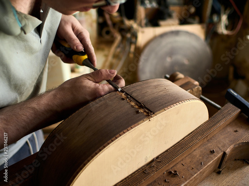 Luthier Install Binding on an guitar. Chamfering on the body of the guitar.