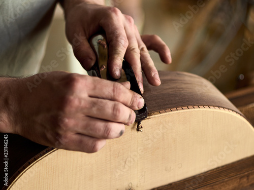 Luthier Install Binding on an guitar. Chamfering on the body of the guitar.